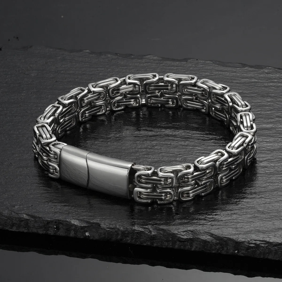 Silberfarbenes Herren-Gliederarmband geschlossen auf dunklem Stein