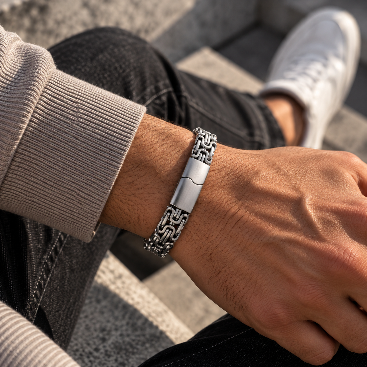 Silberfarbenes Herren-Gliederarmband am Handgelenk zu einem hellen Pullover