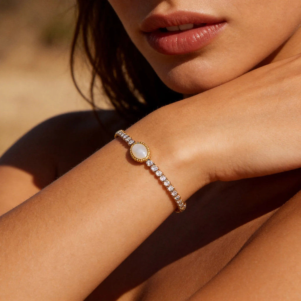 Armband mit rundem, hell schimmerndem Schmuckelement am Handgelenk, Nahaufnahme